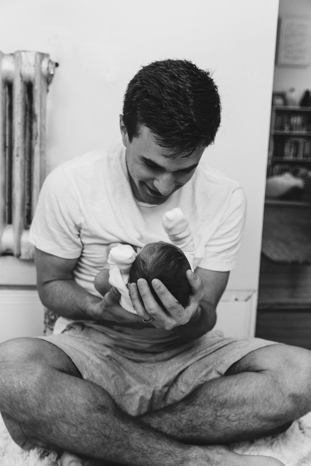 Pai sentado na cama com o bebé nas primeiras semanas de licença parental do pai